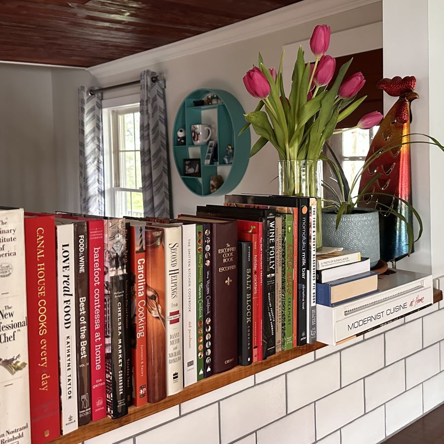 cookbooks on a shelf with tulips and decorative rooster